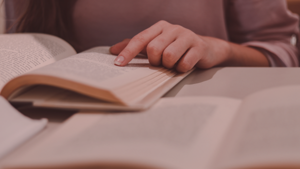 Eine Person liest in einem aufgeschlagenen Buch. 